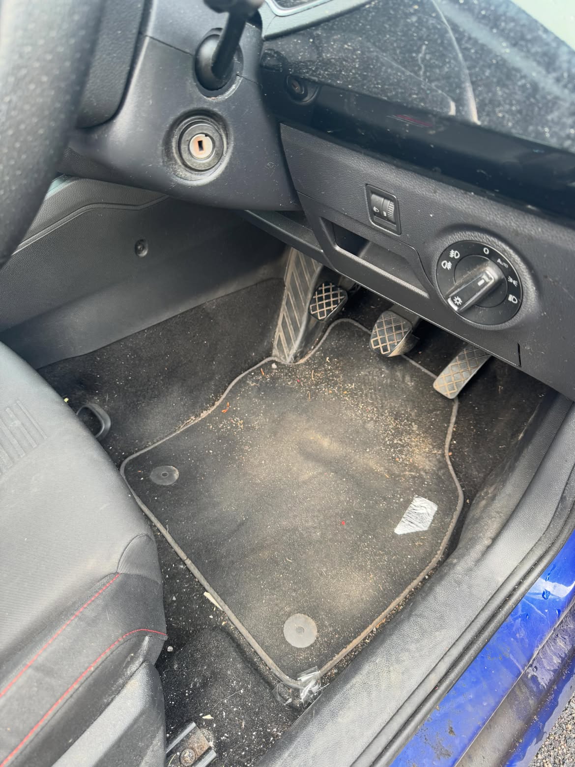 Driver's footwell before cleaning, carpet covered in grit and debris