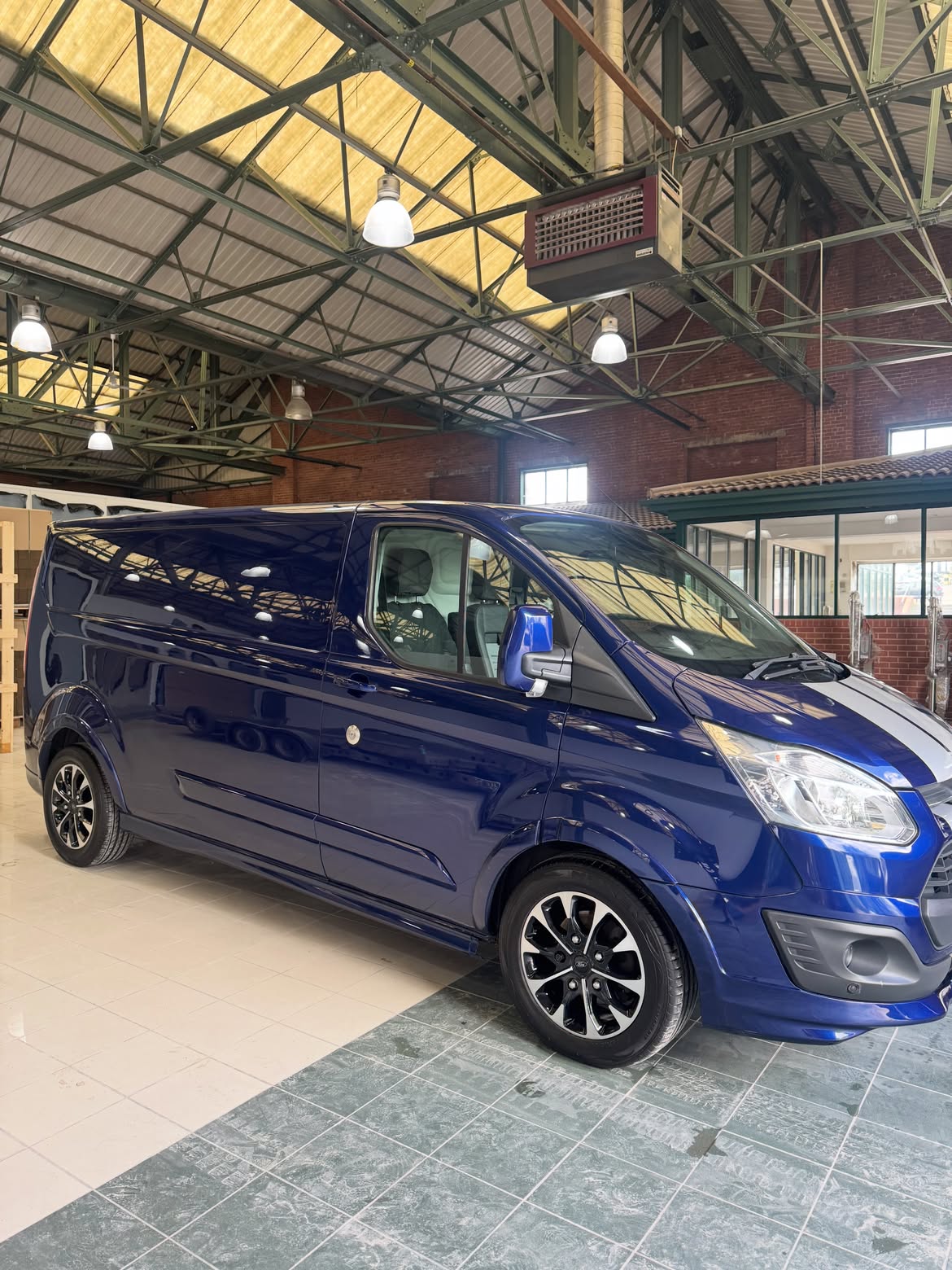 Blue Ford Transit Custom detailed and gleaming inside a workshop