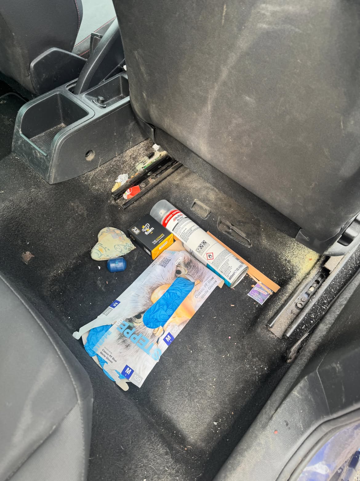 Rear footwell before cleaning, litter and dust across the carpet and rails