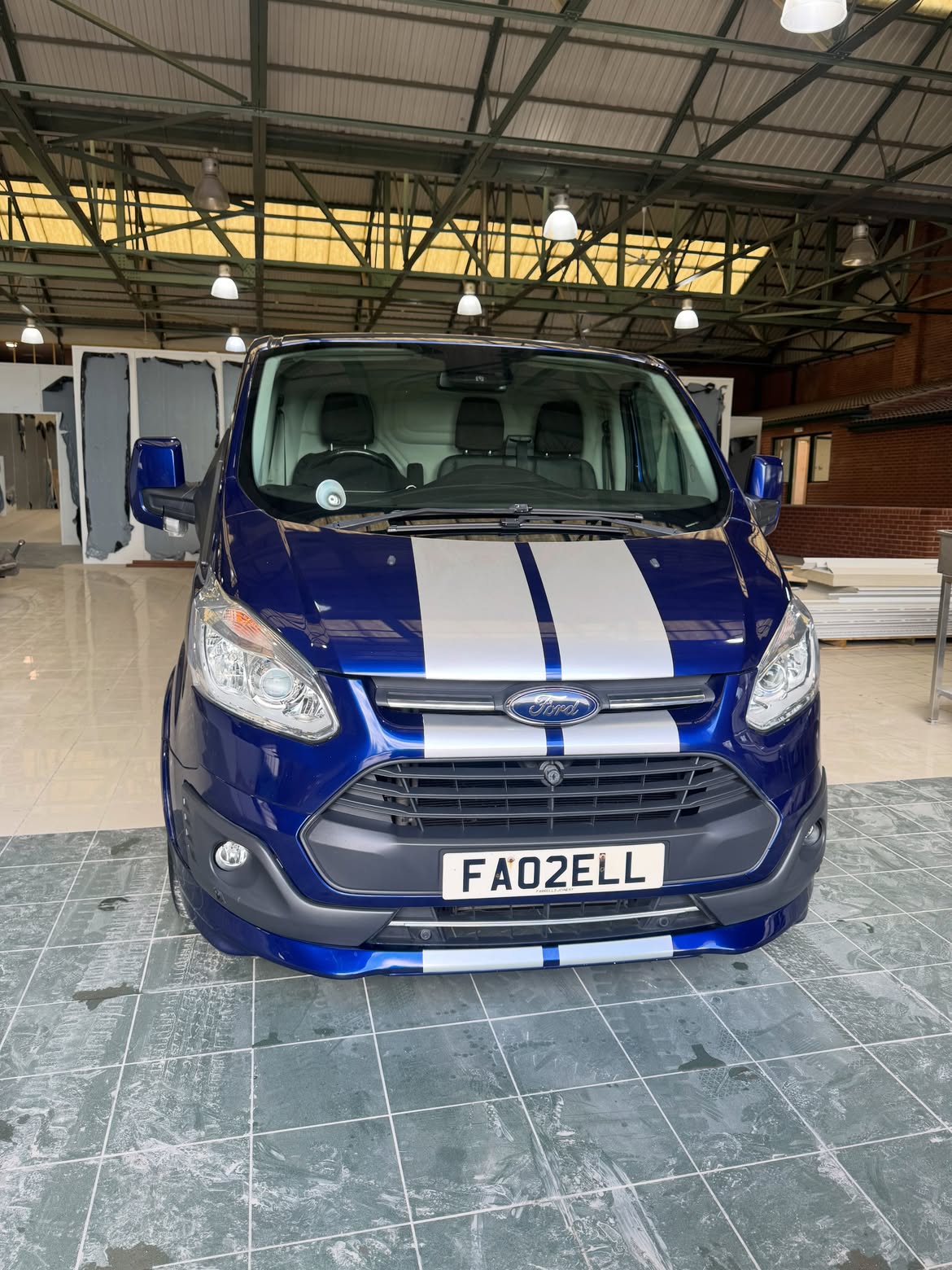 Blue Ford Transit Custom with racing stripes after a maintenance wash
